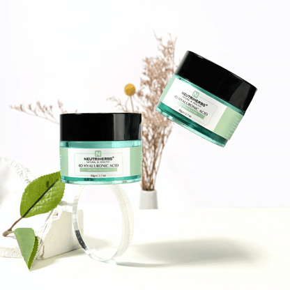 Lifestyle-kuva tuotteesta Neutriherbs 4D Hyaluronic Acid Gel Moisturizer 50 g. Kaksi kosteuttavan geelivoiteen purkkia on esillä vaaleassa ja tyylikkäässä ympäristössä luonnollisilla yksityiskohdilla, jotka välittävät raikasta ihonhoitorutiinia ja intensiivistä kosteutusta.